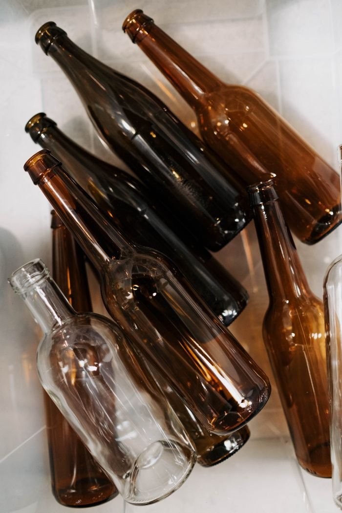 Close-up of assorted empty glass bottles ready for recycling in a plastic container.